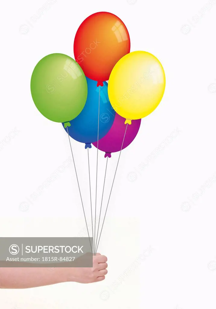 Human hand holding multi coloured balloons