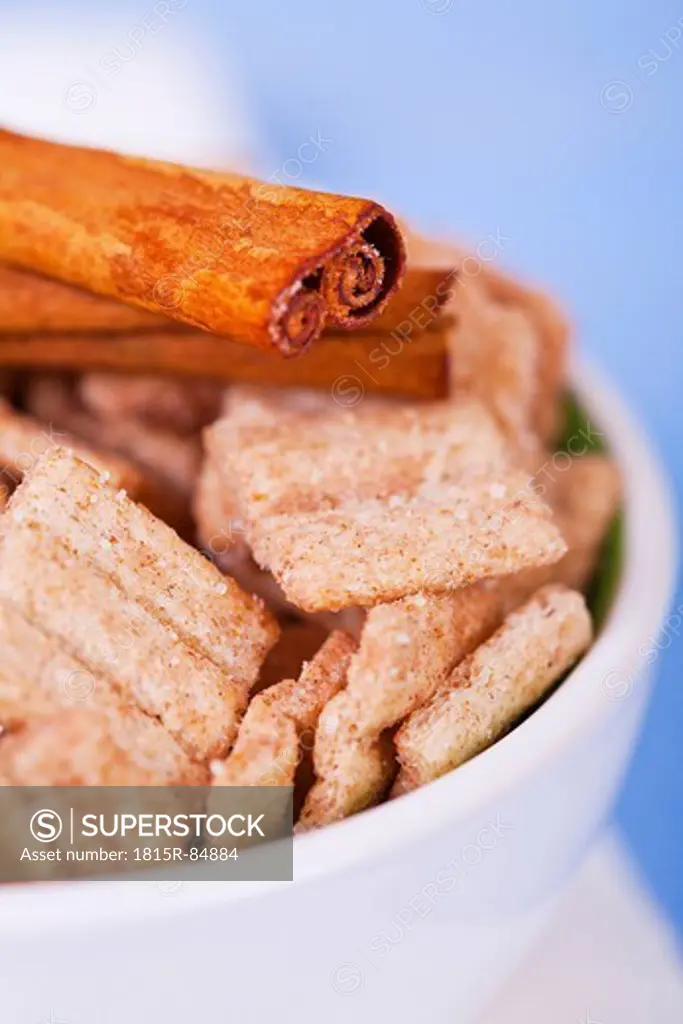 Close up of cinnamon cereal chips in bowl with cinnamon stick on top of it