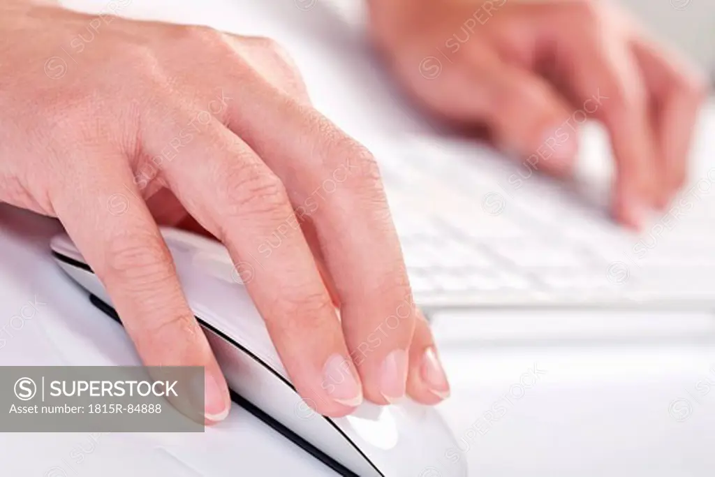 Close up of woman´s hand holding mouse and writing on keyboard