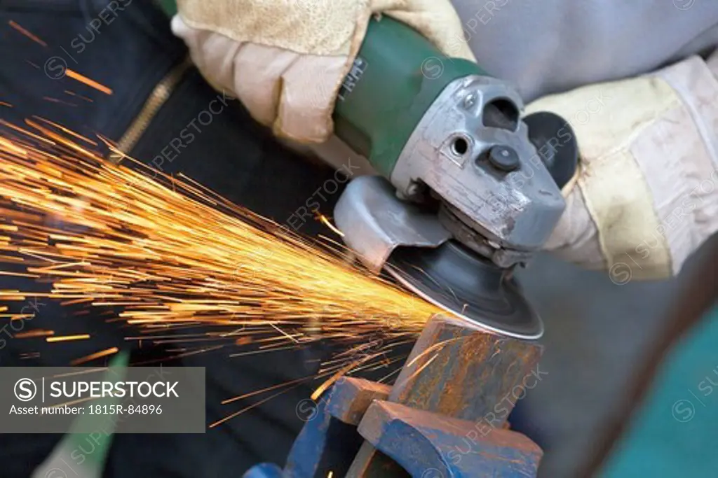 Close up of man sharpening piece of iron with angle grinder