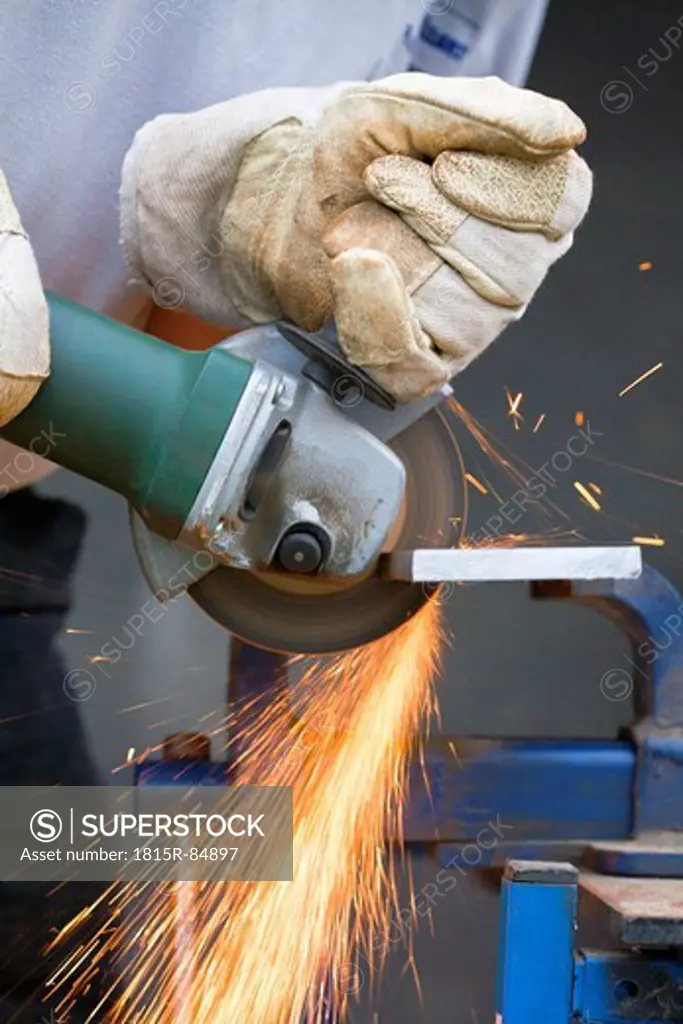 Close up of man cutting piece of iron with angle grinder