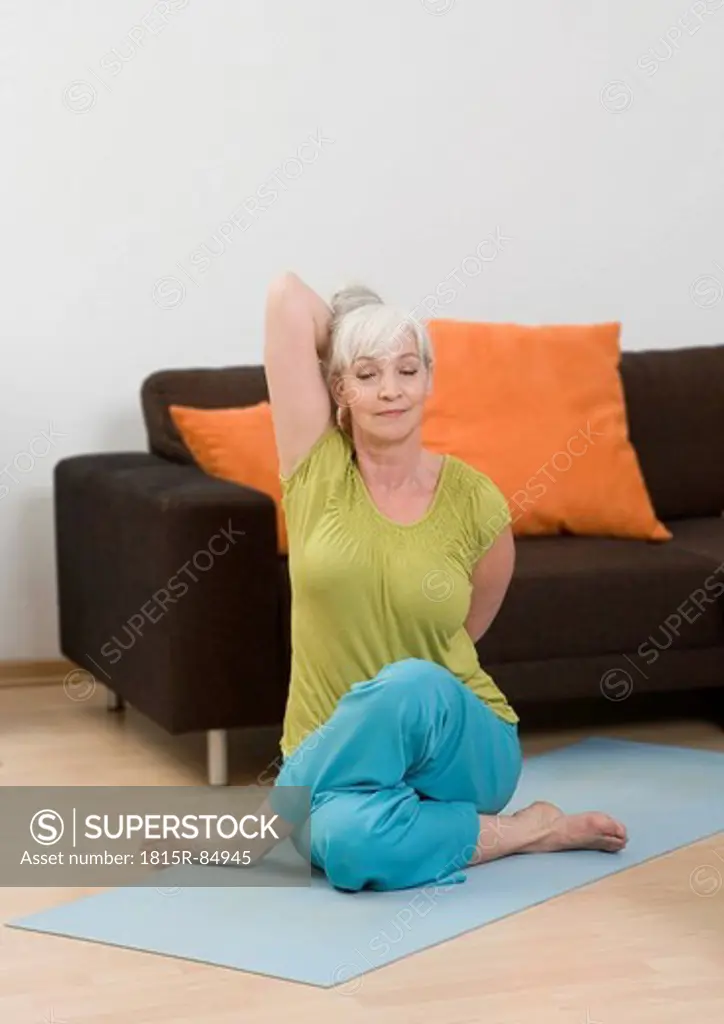 Germany, Duesseldorf, Woman doing yoga near sofa at home