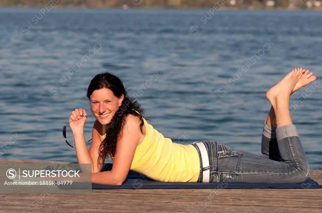 Mid adult woman with book on jetty, smiling, portrait