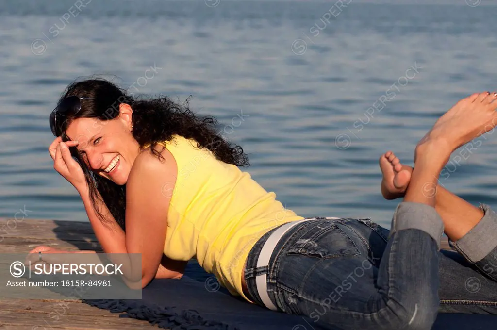 Mid adult woman resting on jetty, smiling, portrait
