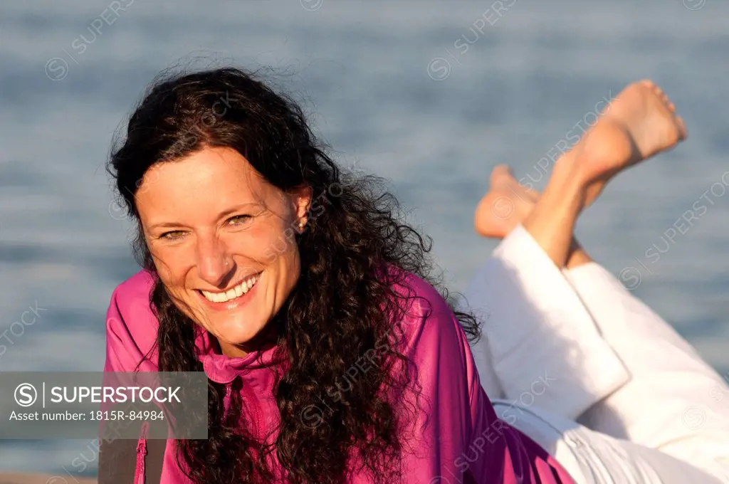 Mid adult woman resting on jetty, smiling, portrait