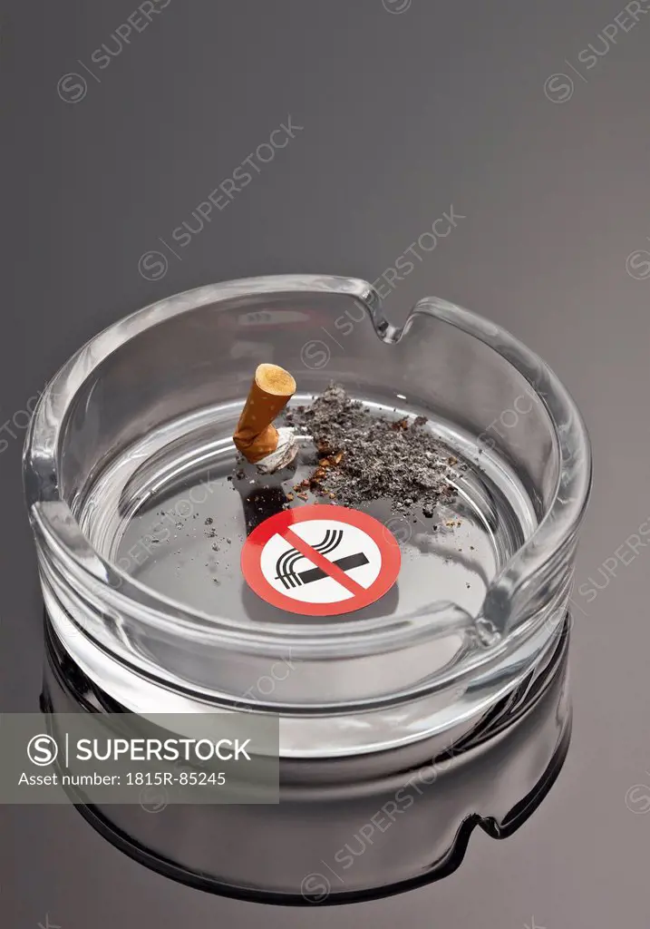 Cigarette in ashtray with no smoking sign