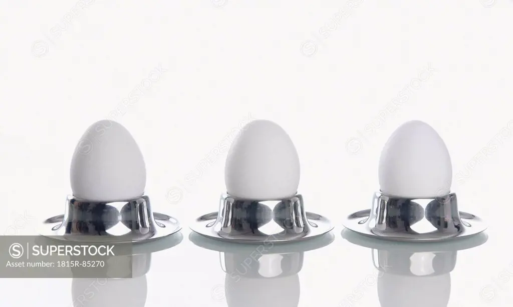 Boiled eggs in egg cup on white background