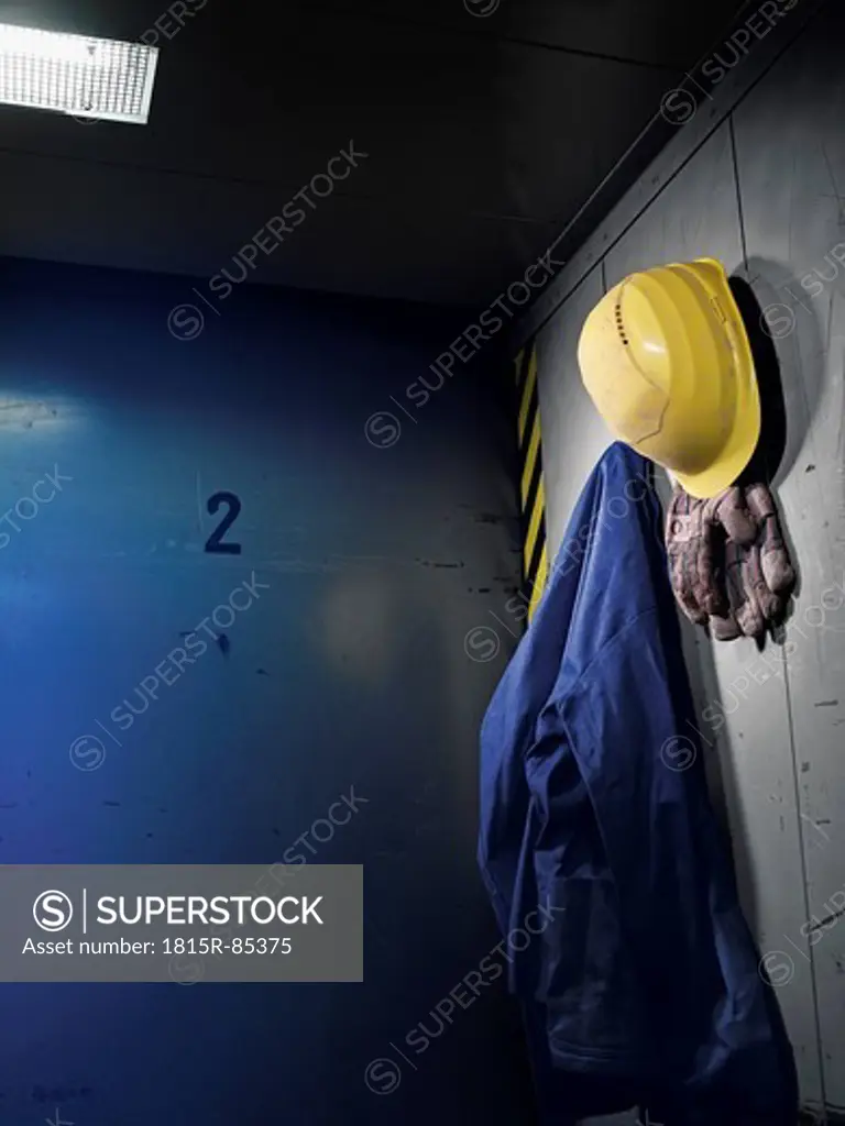 Germany, Work glove, protective workwear and safety helmet hanging in cabin