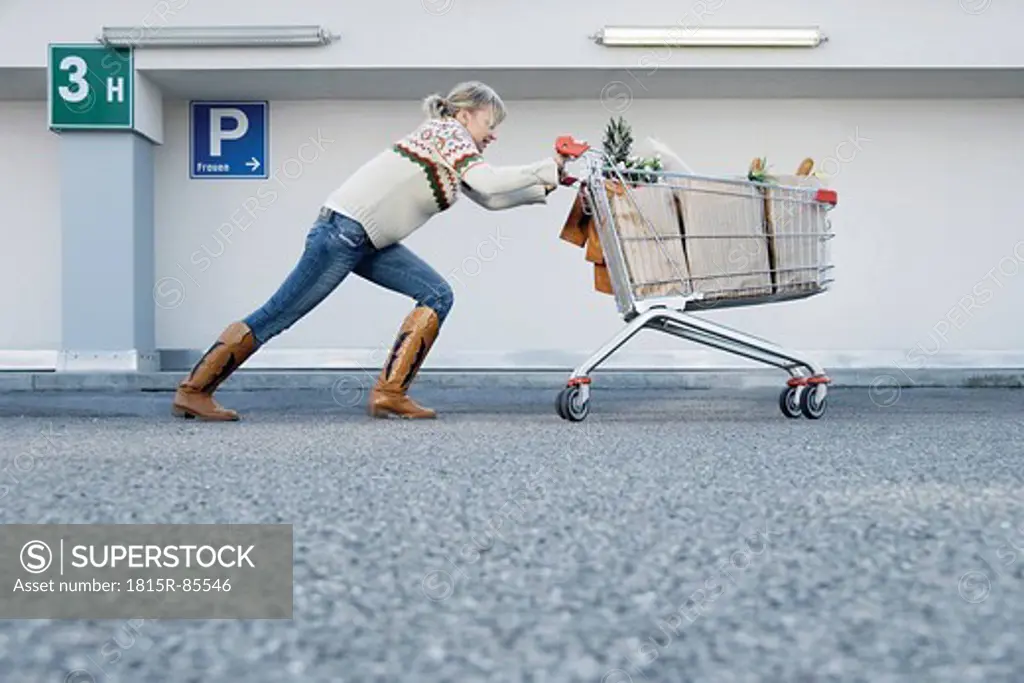 Germany, Young woman pushing shopping cart