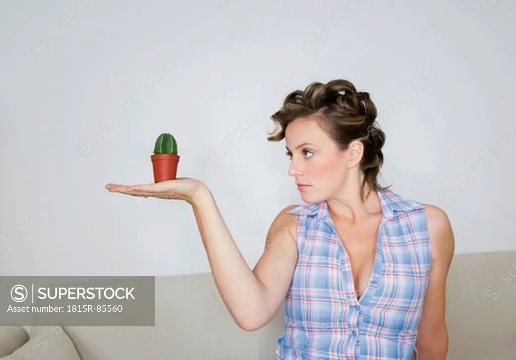 Young woman looking at tiny cactus