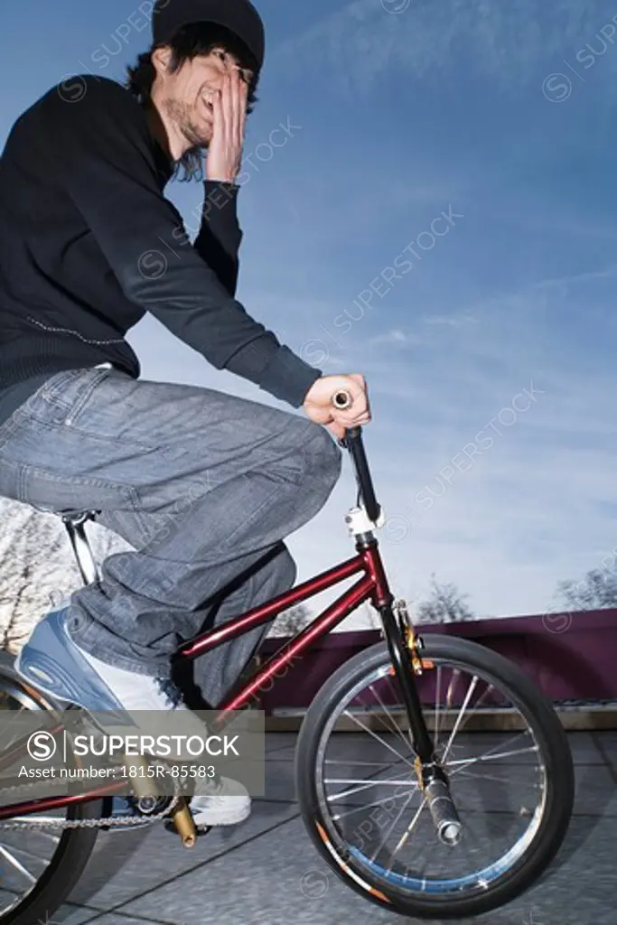 Germany, Stuttgart, Young man on red BMX bike