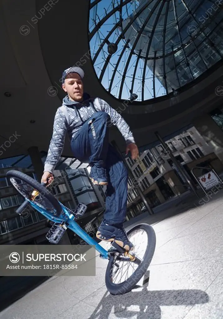 Germany, Stuttgart, Young man performing stunt on bike