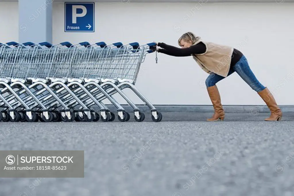 Germany, Young woman pushing shopping carts