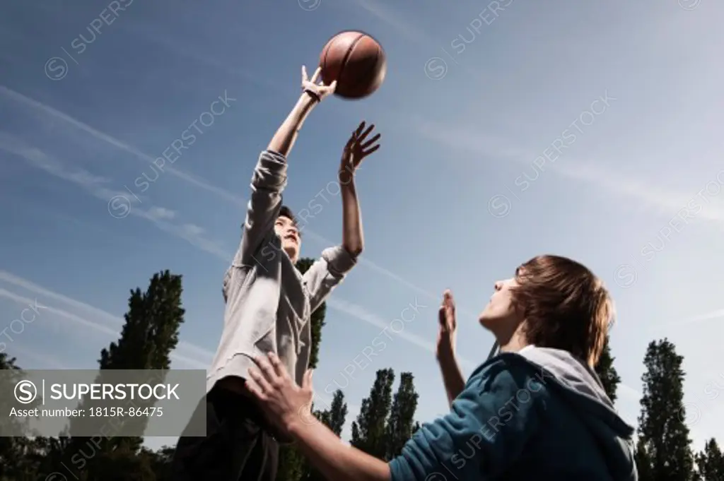Germany, Berlin, Teenage boys basketball in playground