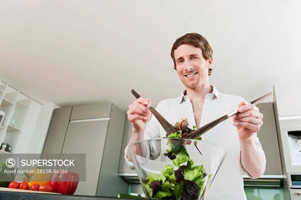 Germany, Hamburg, Man in kitchen mixing vegetable