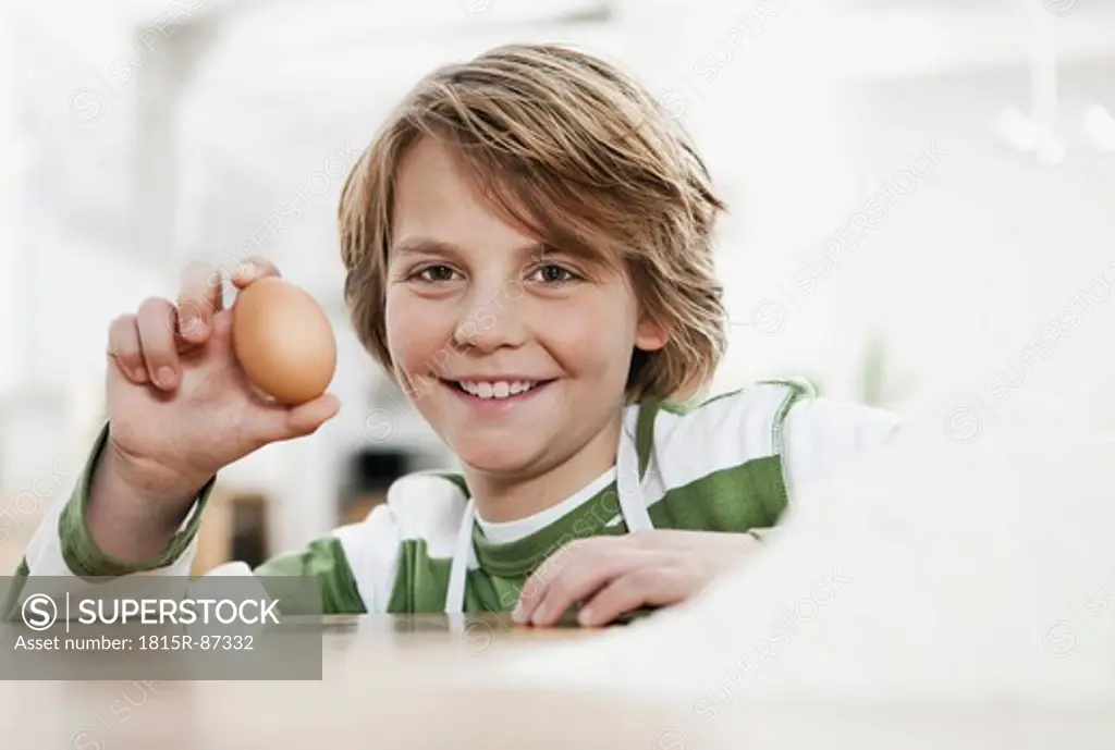 Germany, Cologne, Boy holding egg, smiling, portrait