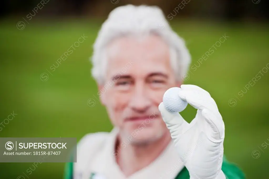 Italy, Kastelruth, Mature man holding golf ball, smiling, portrait
