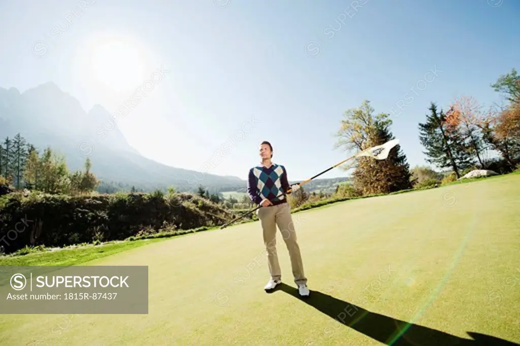 Italy, Kastelruth, Mid adult man holding golf flag on golf course