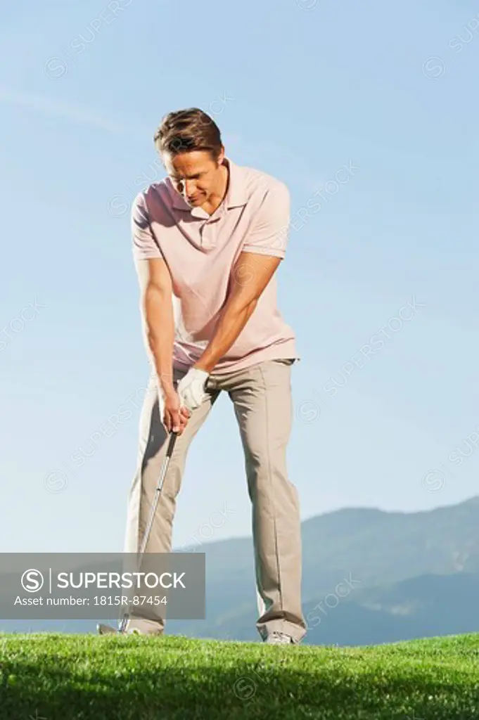 Italy, Kastelruth, Mid adult man playing golf on golf course
