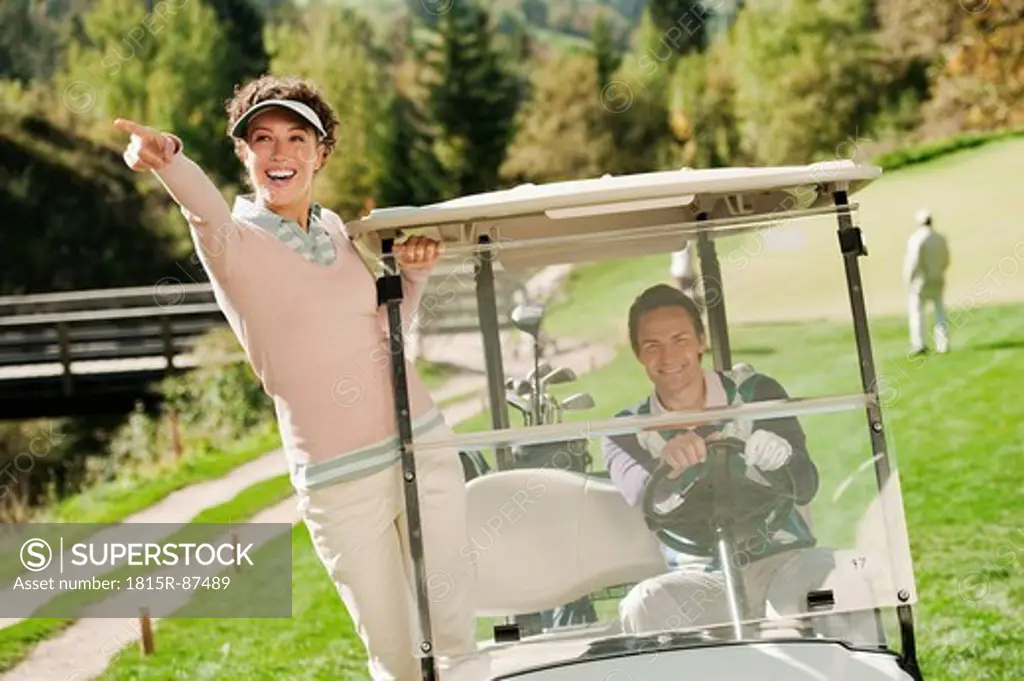Italy, Kastelruth, Golfers in golf cart on golf course, smiling