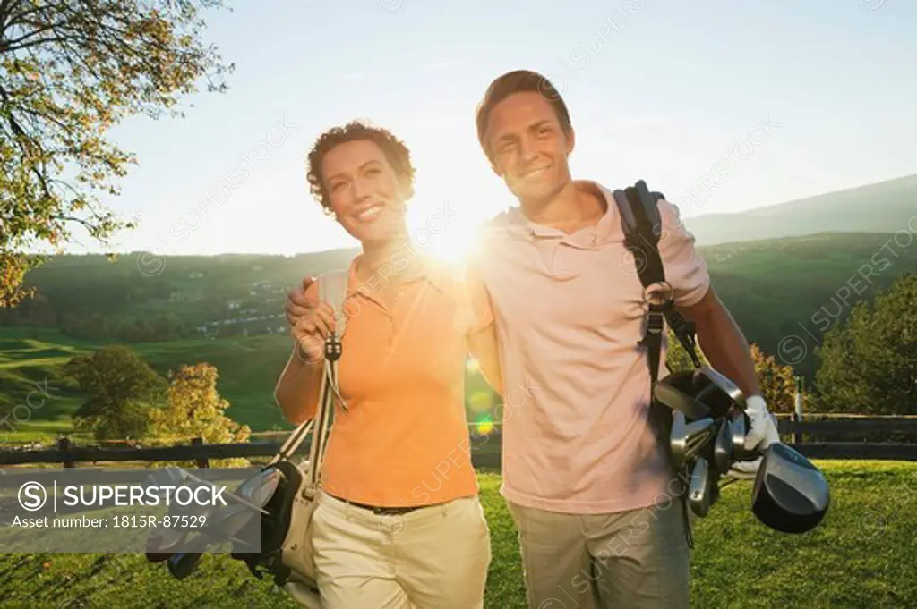 Italy, Kastelruth, Golfers with golf bag walking and smiling