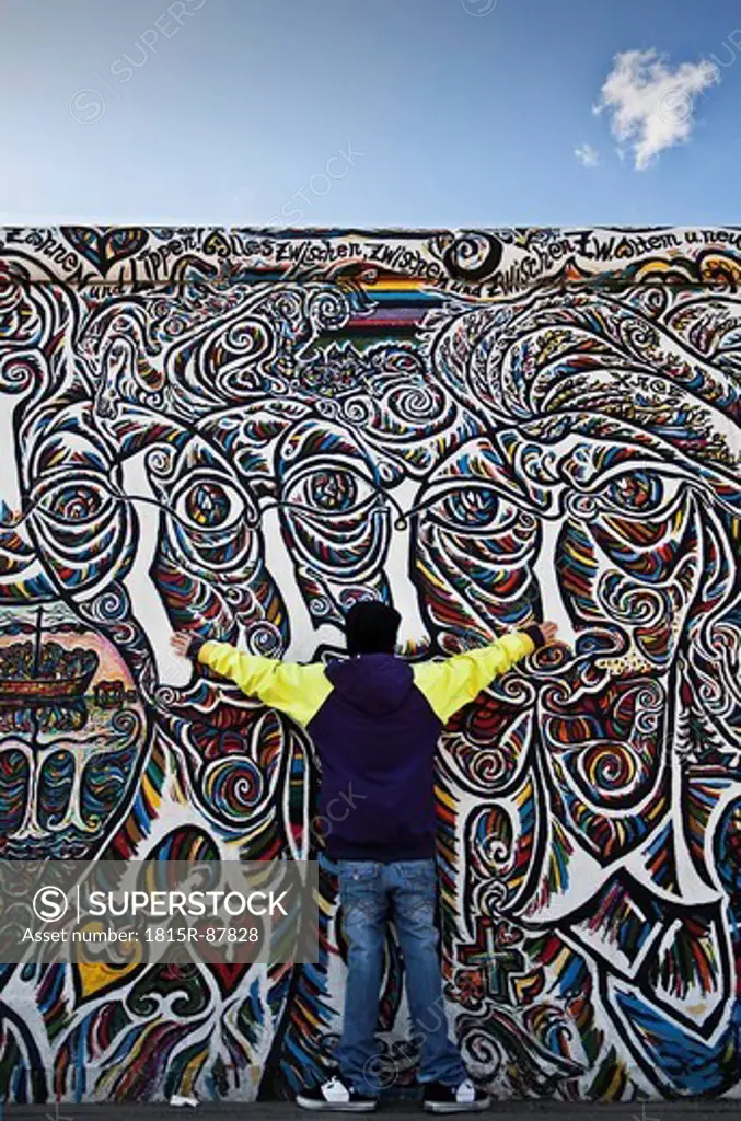 Germany, Berlin, Teenage boy standing against berlin wall