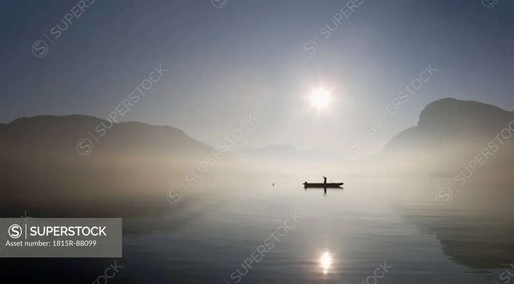 Austria, Mondsee, View of fishing boat in lake with foggy morning
