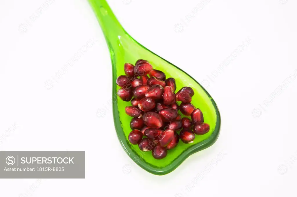 Pomegranate seeds on plastic spoon, elevated view