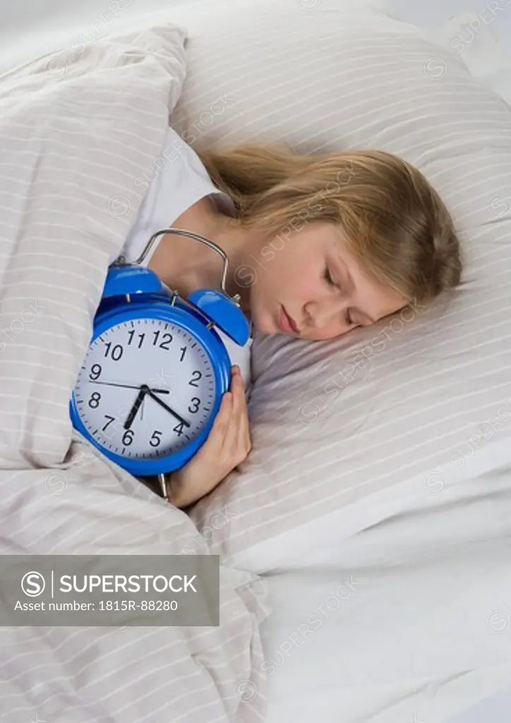 Girl sleeping on bed with alarm clock