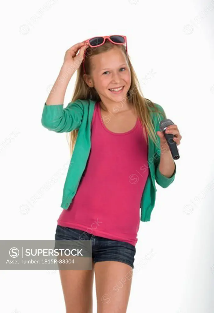 Girl dancing holding microphone against white background, smiling, portrait