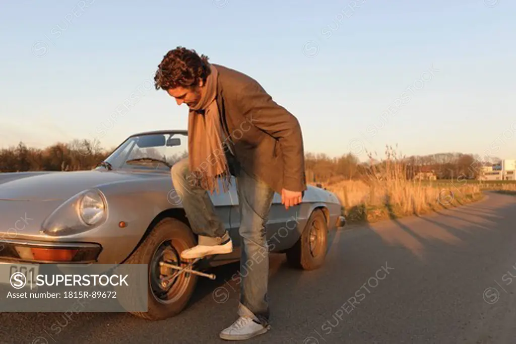 Germany, Hamburg, Man changing tyre of classic cabriolet car