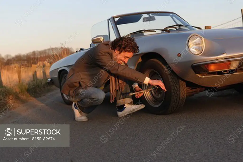 Germany, Hamburg, Man changing tyre of classic cabriolet car