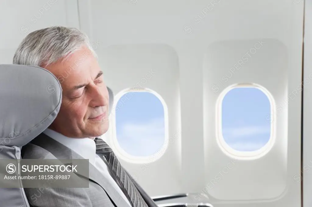 Germany, Bavaria, Munich, Senior businessman sleeping in business class airplane cabin
