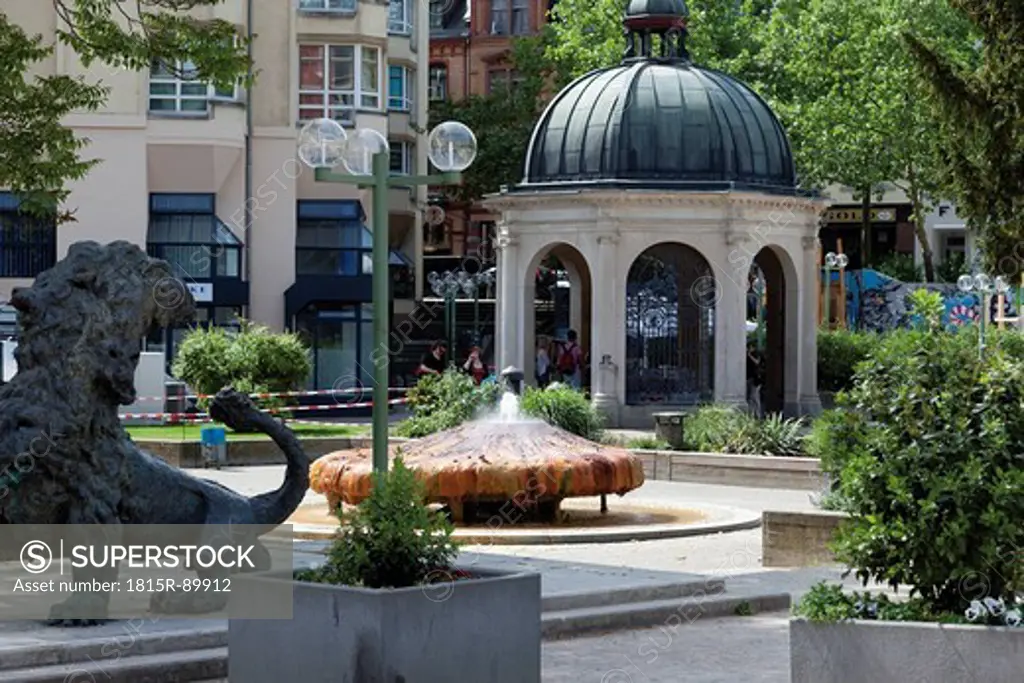 Europe, Germany, Hesse, Wiesbaden, Kochbrunnenplatz, View of hot thermal spring well with fountain and lion statue in foreground