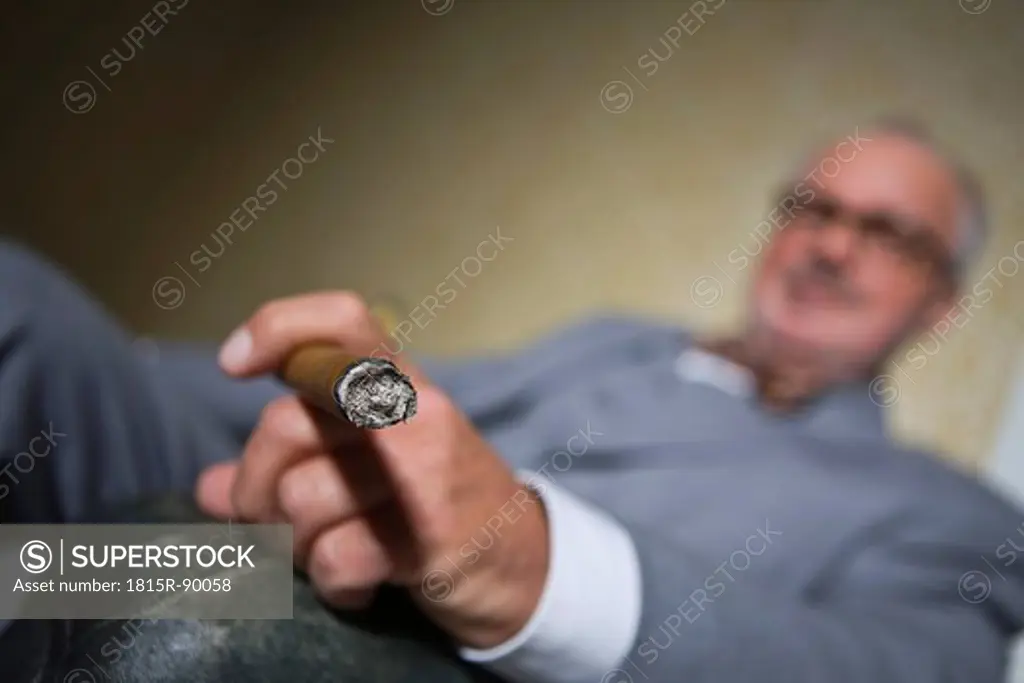 Germany, Braunschweig, Senior man smoking cigar, close up