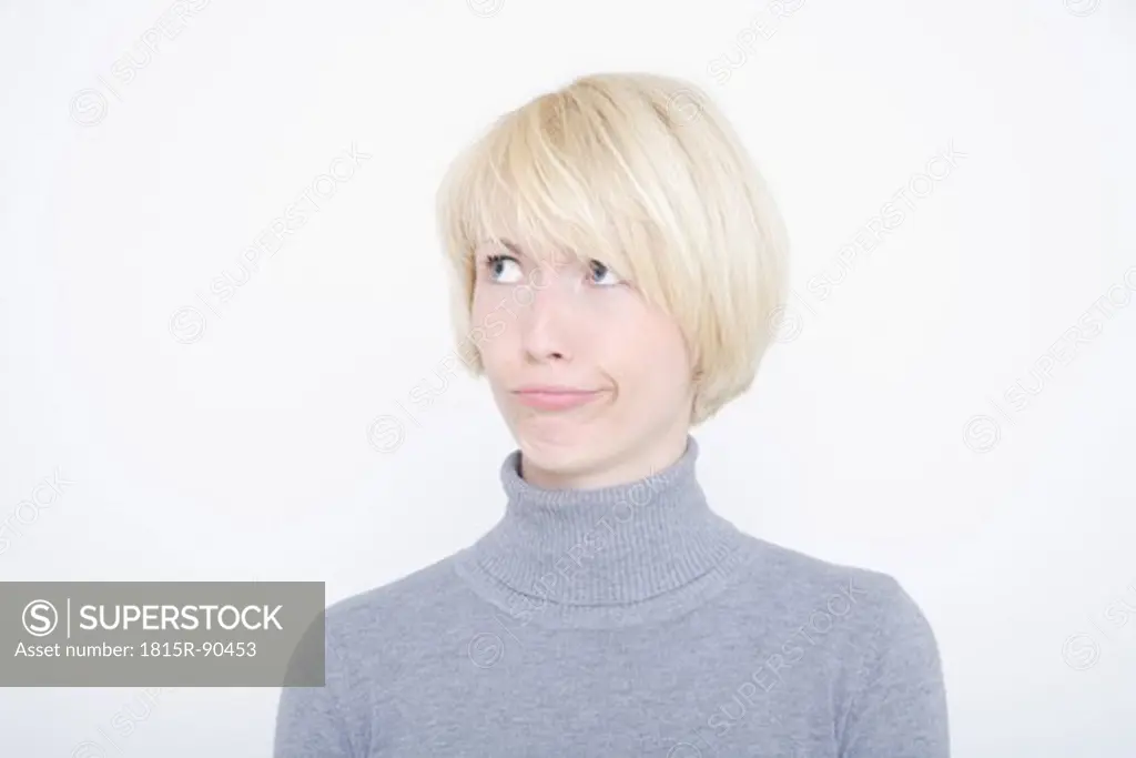 Young woman grimacing against white background, close up