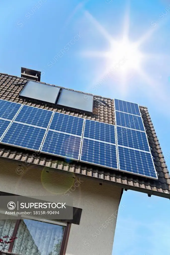 Germany, Cologne, Solar panels on rooftop against blue sky and sun