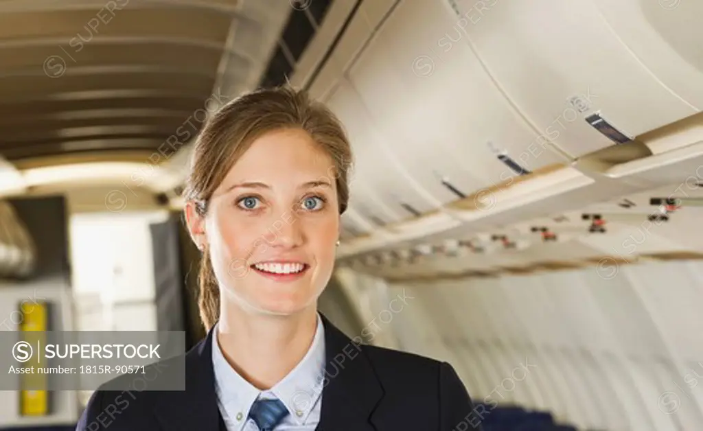 Germany, Munich, Bavaria, Close up of stewardess in economy class airliner, smiling, portrait