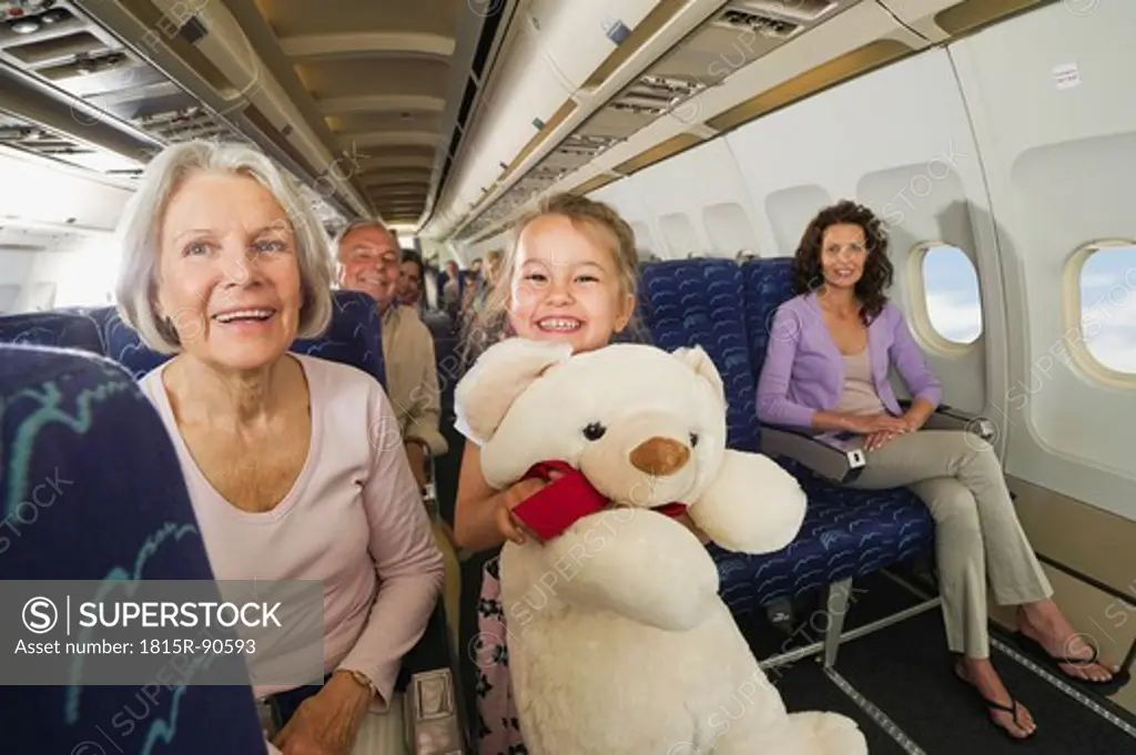 Germany, Munich, Bavaria, Girl holding teddy bear in economy class airliner