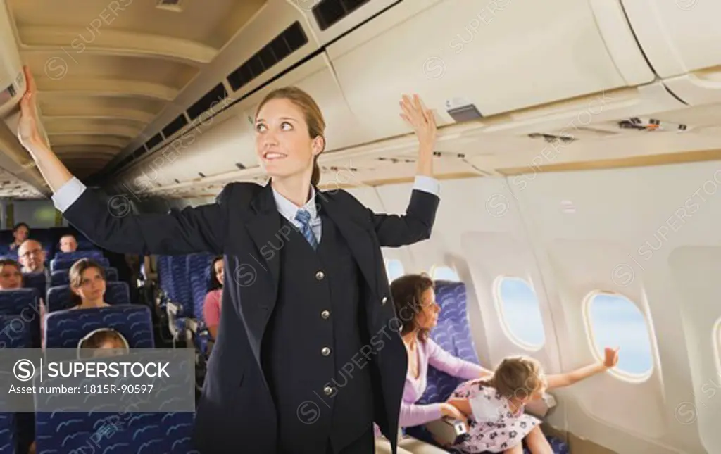 Germany, Munich, Bavaria, Stewardess checking lockers in economy class airliner