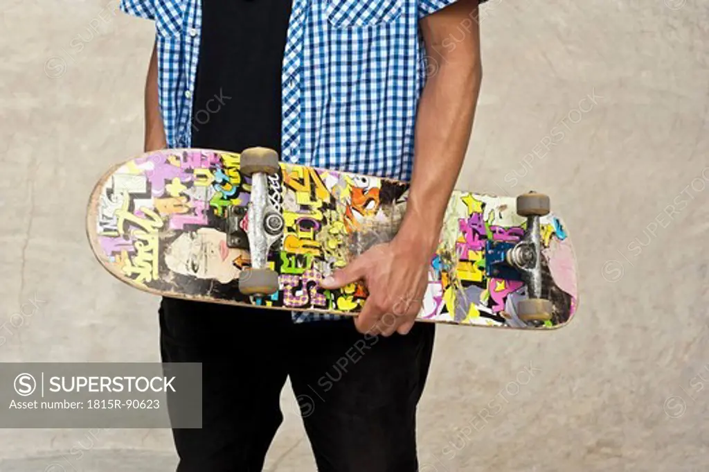 Germany, Düsseldorf, Close up of skateboarder holding his deck in public skatepark