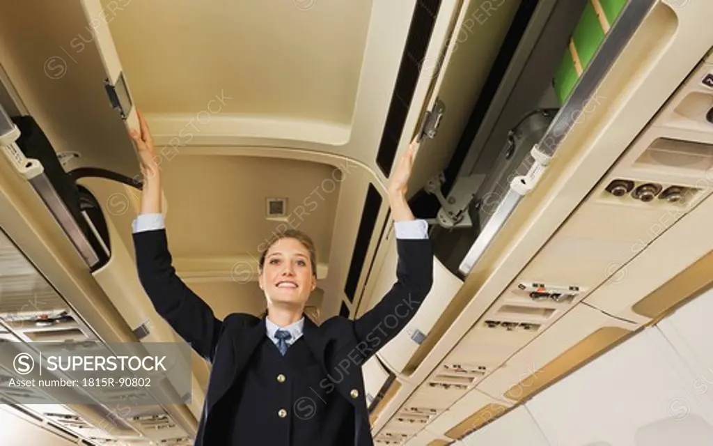 Germany, Munich, Bavaria, Stewardess closing safety lockers in economy class airliner