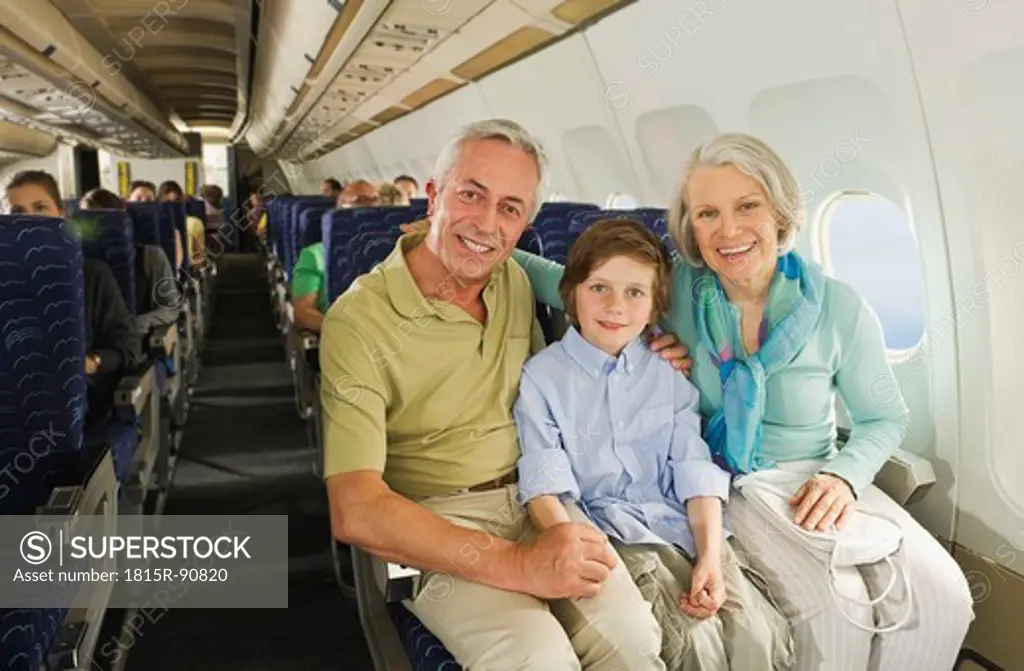 Germany, Munich, Bavaria, Boy sitting besides senior people in economy class airliner