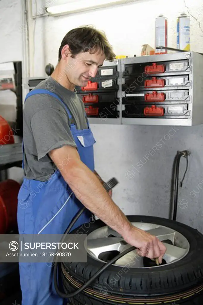 Germany, Ebenhausen, Mechatronic technician working on tyre in car garage