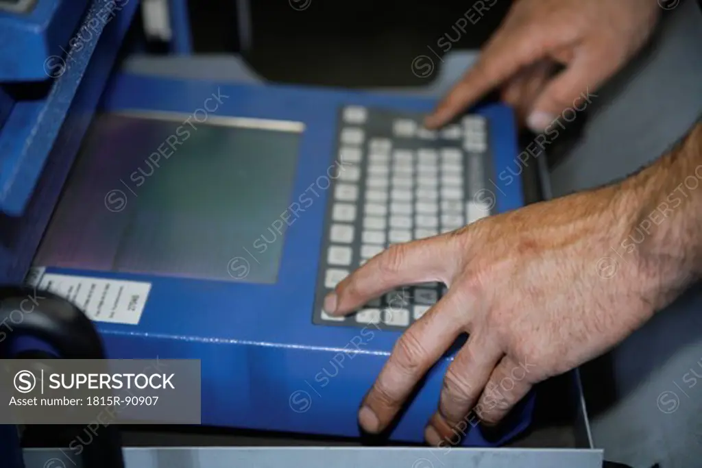 Germany, Ebenhausen, Mechatronic technician working on computer in car garage, close up