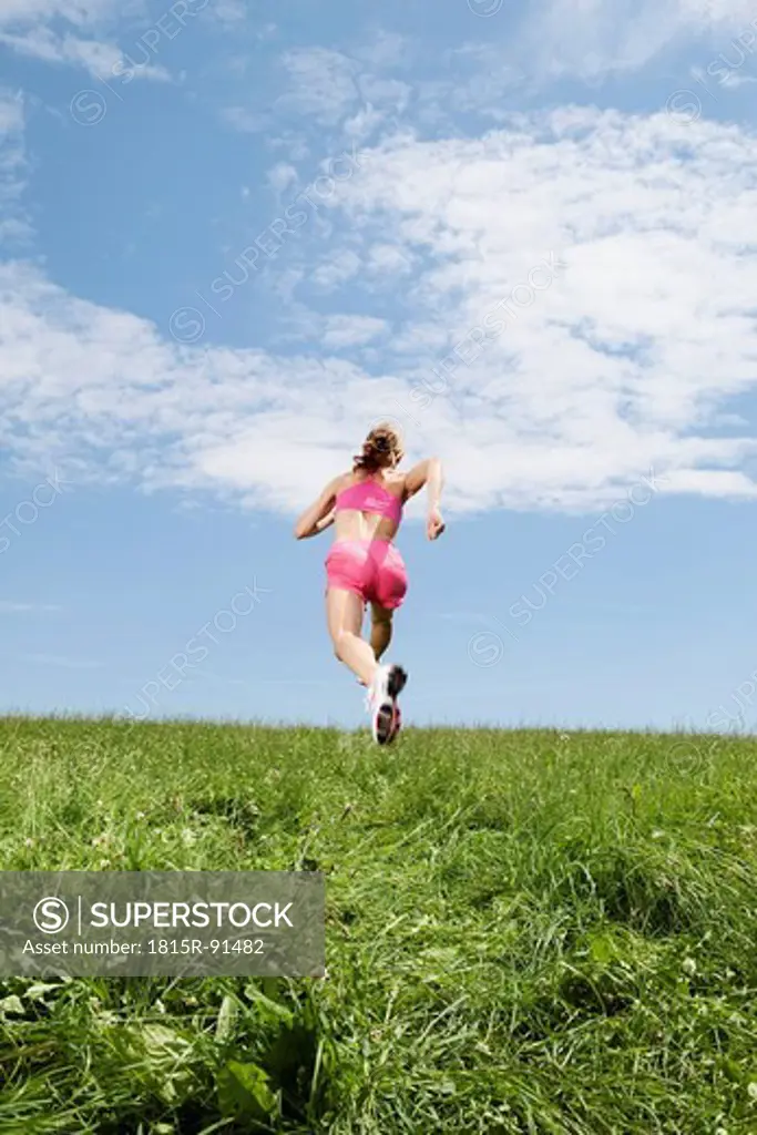 Germany, Bavaria, Young woman running on grass