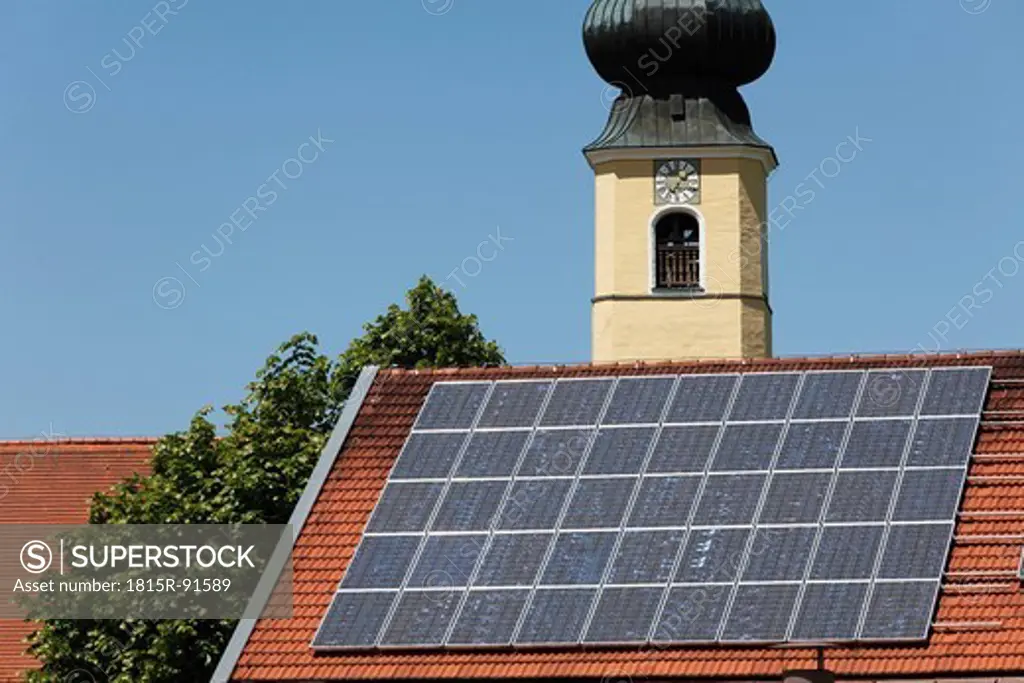 Germany, Bavaria, Upper Bavaria, Frauenried, View of solar collector on roof and church tower in background