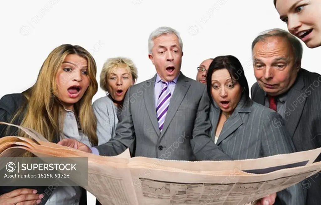 Business people shocked while reading newspaper against white background