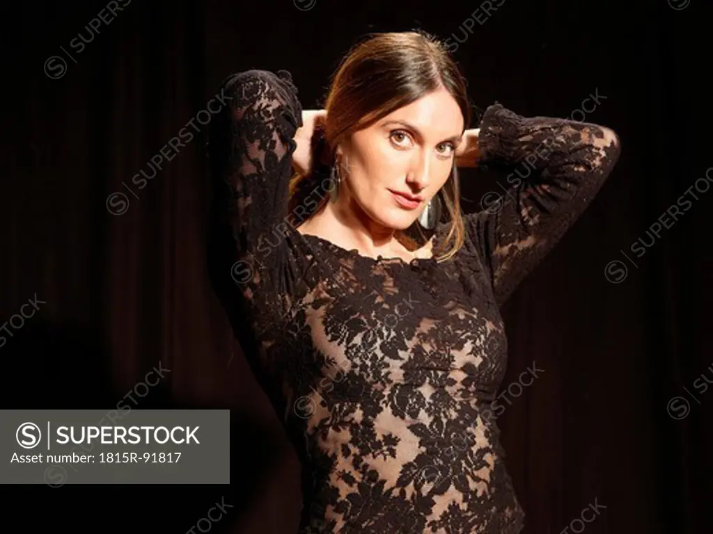Spanish woman in black netted dress against black background, portrait