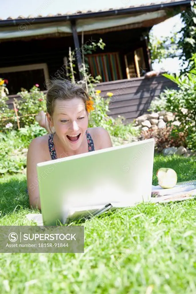 Woman using laptop while lying on grass